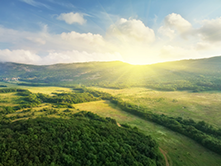 Green mountain range with sun in background